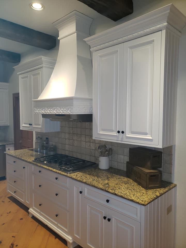 White refinished kitchen cabinets with a custom painted range hood and beaded trim