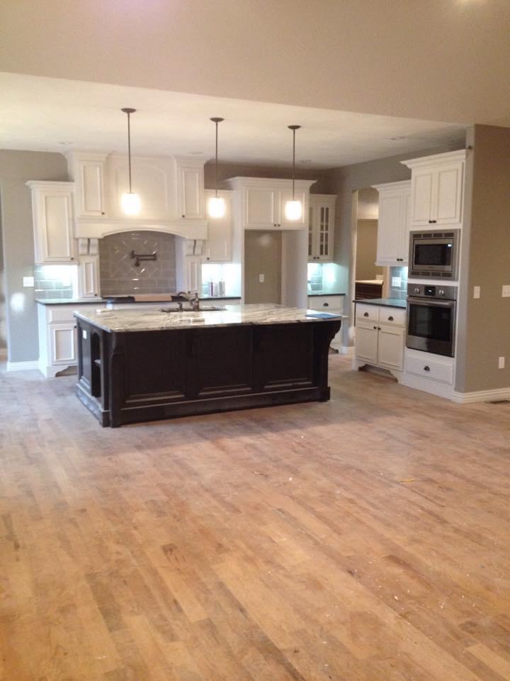 White painted kitchen cabinets with a dark stained island and double wall ovens