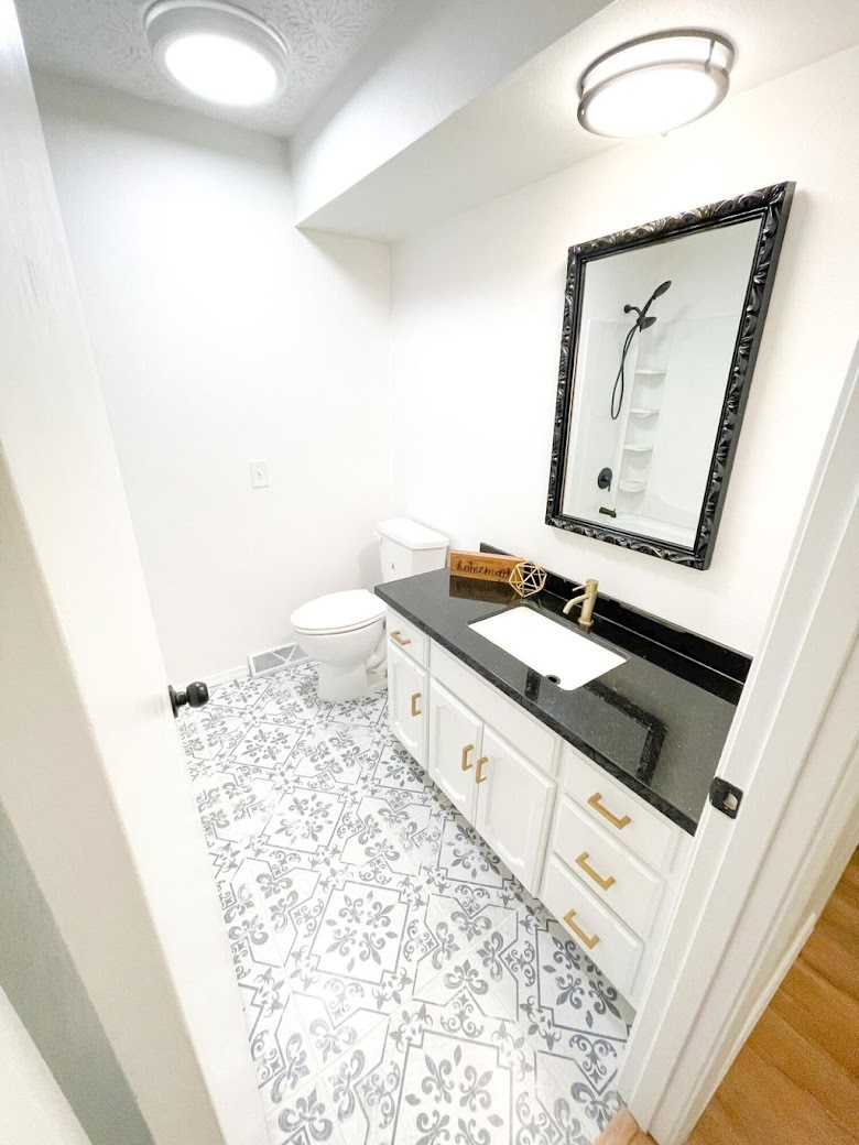 White painted bathroom vanity cabinets with gold hardware and a black countertop