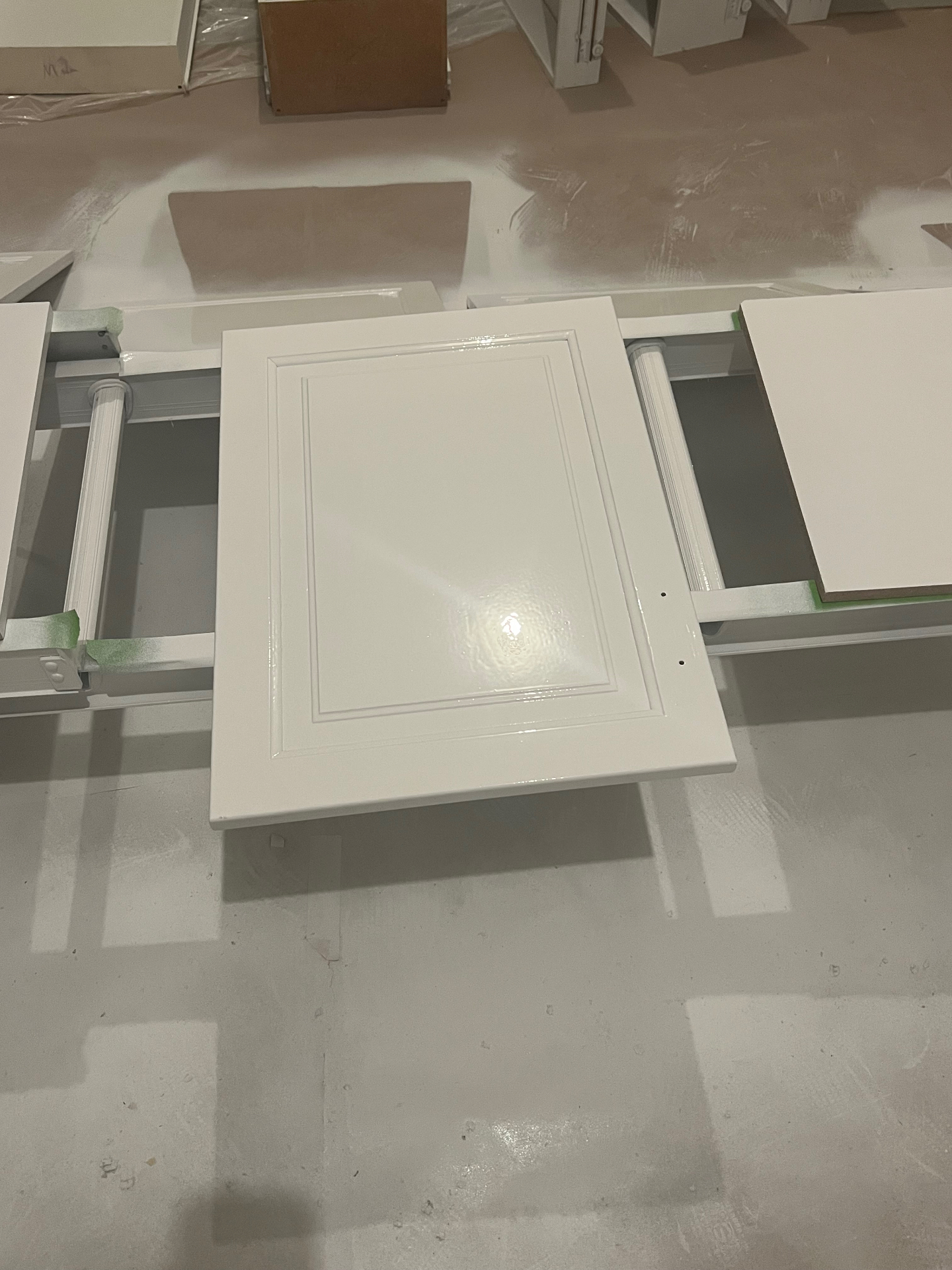 Freshly sprayed white cabinet door drying on racks in the finishing shop